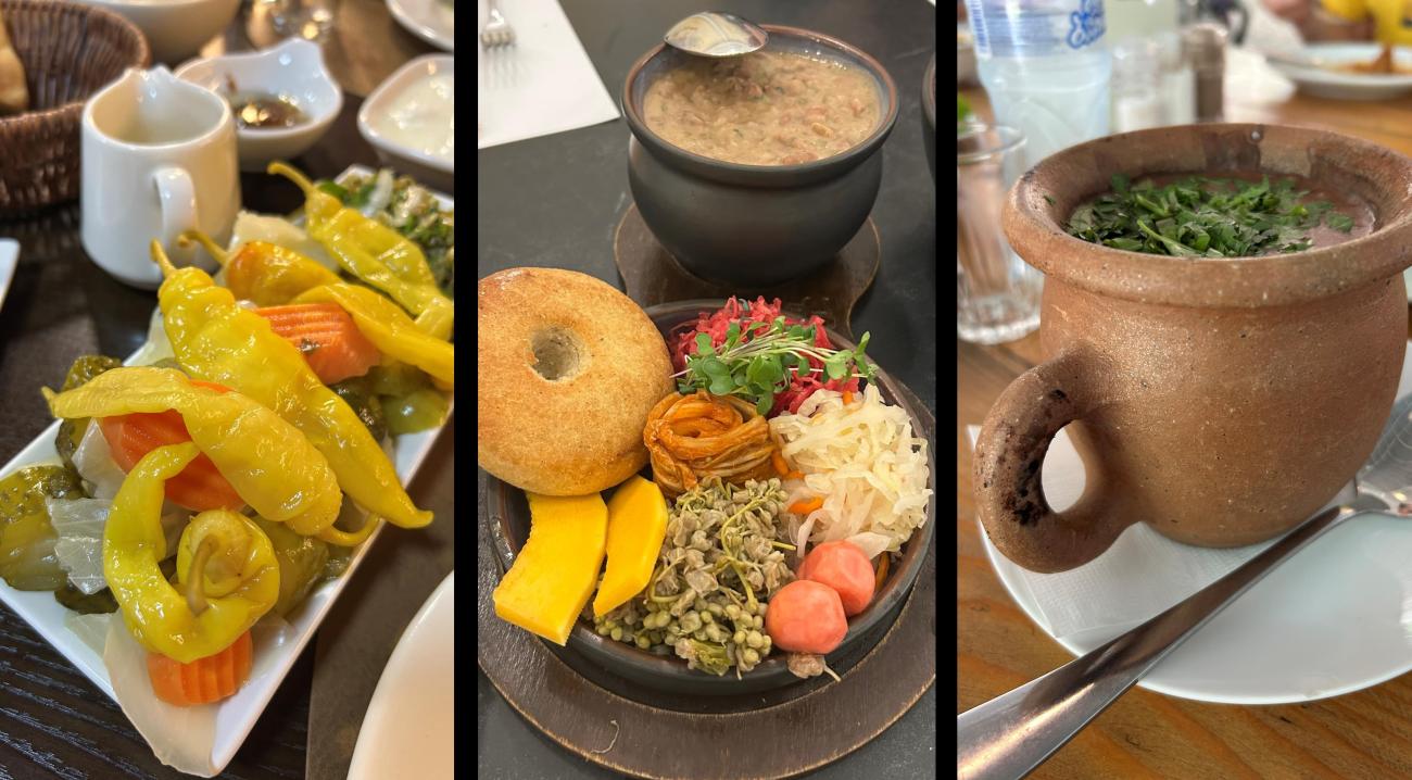 A beautifully presented plate of traditional Georgian cornbread and vibrant pickles sits next to a clay pot of slow-cooked beans